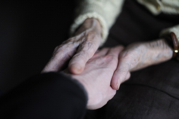 A woman, suffering from Alzheimer's desease, holds the hand of a relative on March 18, 2011 in a retirement house in Angervilliers, eastern France.   AFP PHOTO / SEBASTIEN BOZON (Photo credit should read SEBASTIEN BOZON/AFP/Getty Images)
